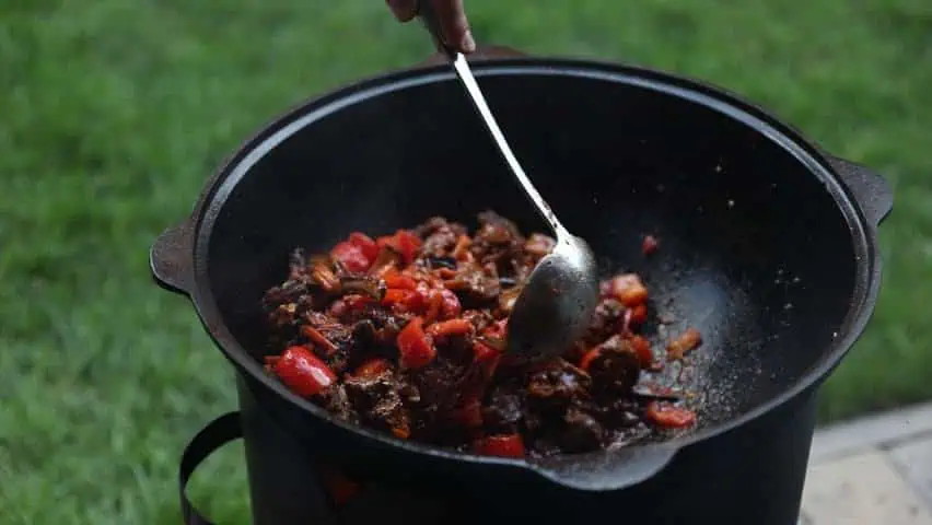 Запечённое мясо с овощами в казане на улице.