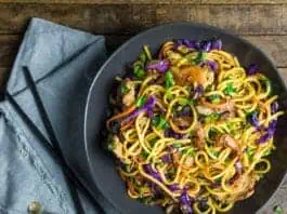 Запечённые лапша с овощами и курицей, азиатский стиль, в миске, на деревянном столе.